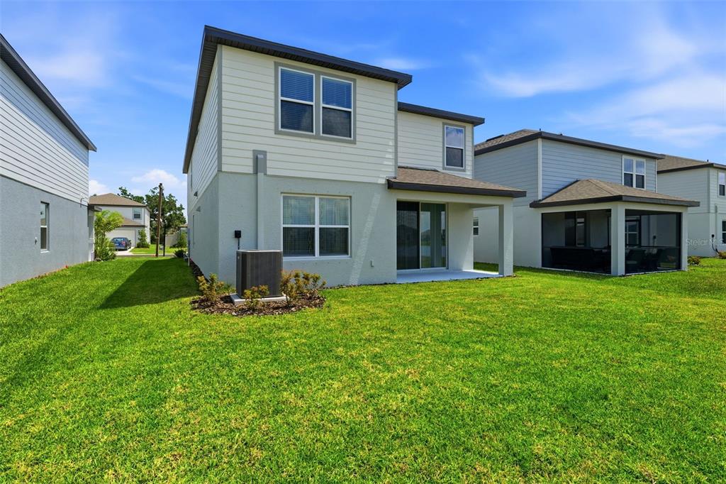 The rear exterior of a two-story house features a covered patio and a grassy yard — 10517 HIDDEN BANKS GLEN, PARRISH, FL