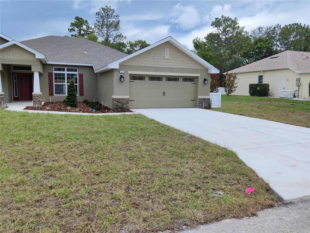 A single-story house with a tan stucco exterior, a two-car garage, and a concrete driveway — 1 CHRYSANTHEMUM COURT, HOMOSASSA, FL