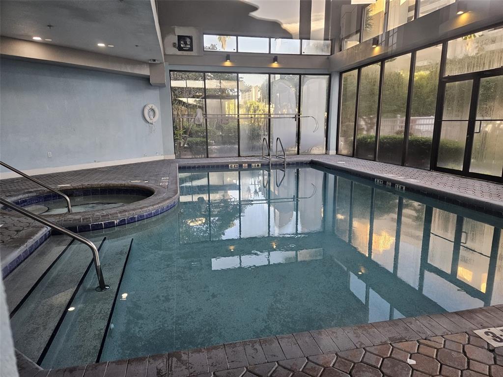 An indoor swimming pool and hot tub area with large windows and tiled flooring — 6165 CARRIER DRIVE UNIT 3201, ORLANDO, FL