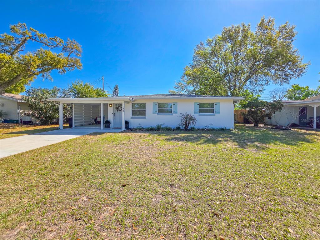 A single-story white house with a carport and blue shutters sits on a grassy lot — 1807 GOLFVIEW BOULEVARD, SOUTH DAYTONA, FL