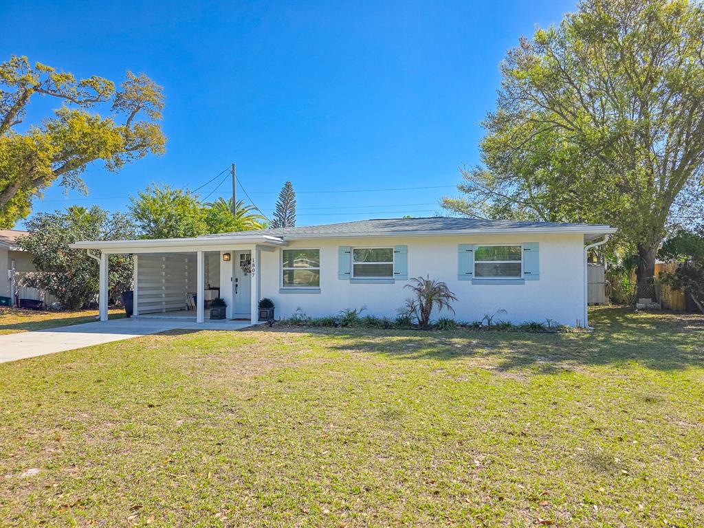 A single-story white house with a carport and light blue shutters sits on a lawn — 1807 GOLFVIEW BOULEVARD, SOUTH DAYTONA, FL