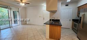 A kitchen with a breakfast bar and tile flooring opens to a living area with balcony — 6386 Emerald Dunes Dr, West Palm Beach FL 33411, WEST PALM BEACH, FL