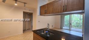 A kitchen features dark granite countertops, wood cabinets, and a view of trees outside — 6386 Emerald Dunes Dr, West Palm Beach FL 33411, WEST PALM BEACH, FL