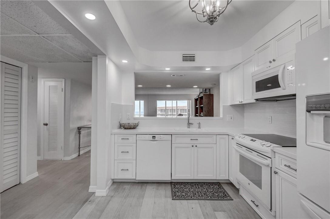 A bright kitchen features white cabinetry, stainless steel appliances, and light wood-look flooring — 2871 N Ocean Boulevard # C519, Boca Raton FL 33431, BOCA RATON, FL