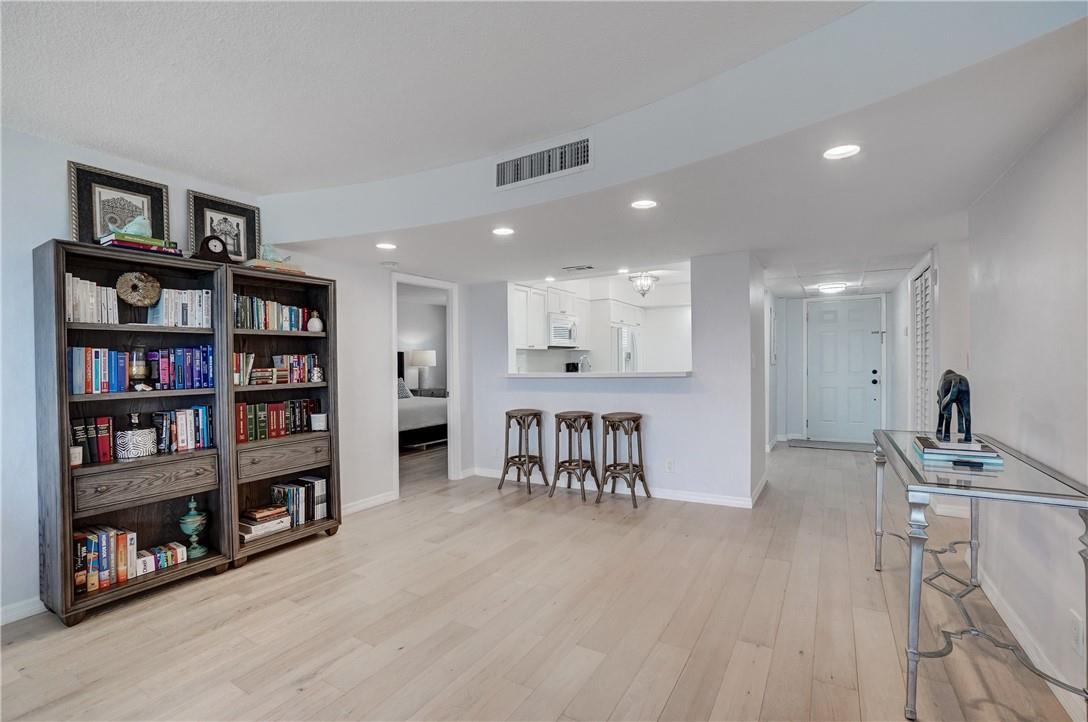 A living area with light wood floors, a bookshelf, a breakfast bar, and an entryway — 2871 N Ocean Boulevard # C519, Boca Raton FL 33431, BOCA RATON, FL
