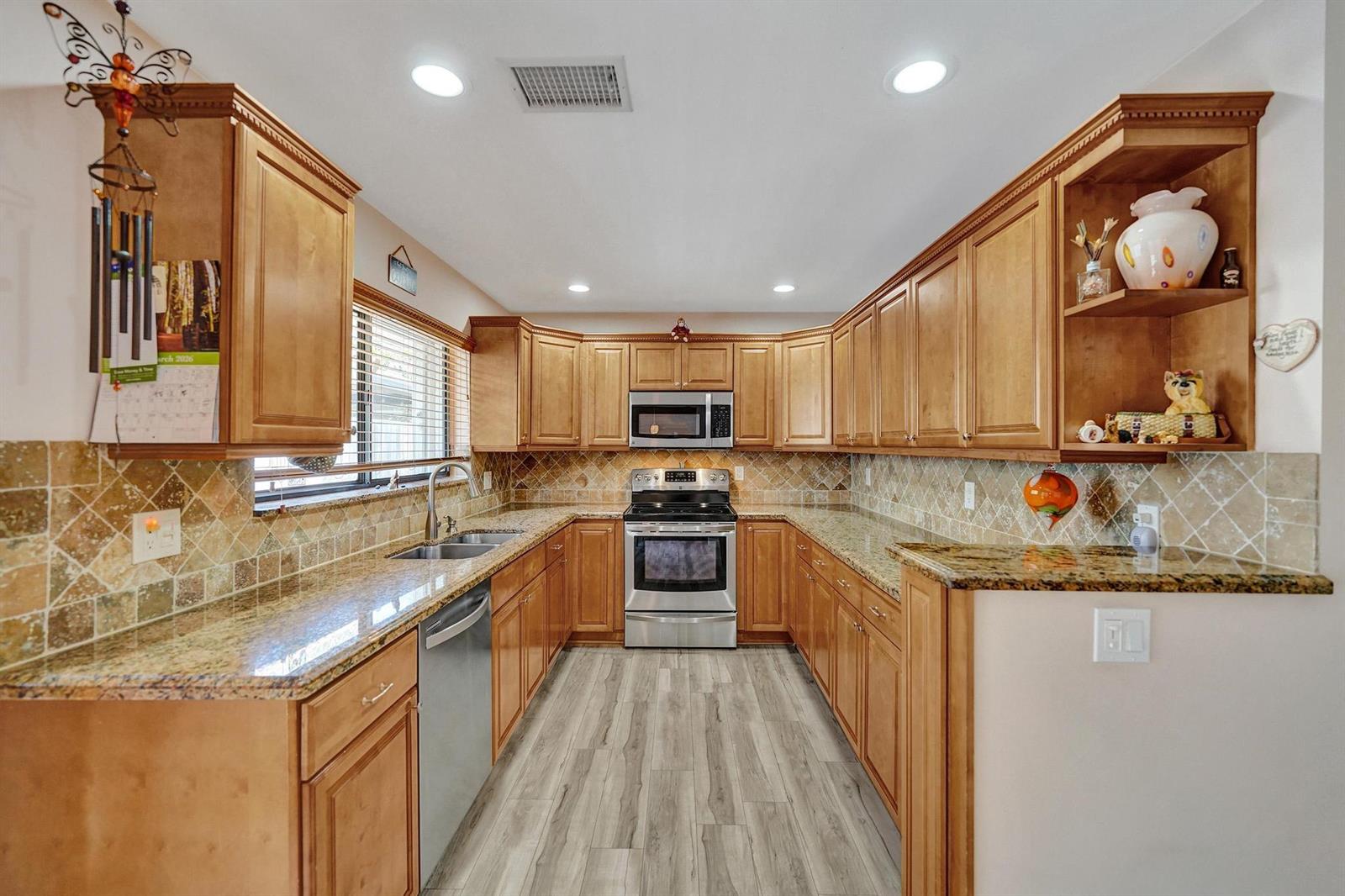 A kitchen features light wood cabinets, granite countertops, stainless steel appliances, and a tiled backsplash — 9355 NW 18th Drive, Plantation FL 33322, PLANTATION, FL