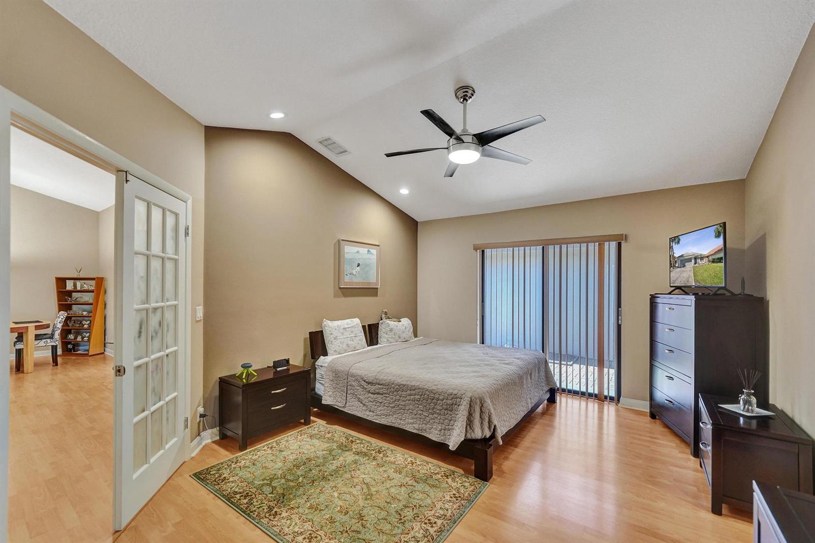 A bedroom with a vaulted ceiling, wood flooring, a queen bed, and a sliding glass door — 9355 NW 18th Drive, Plantation FL 33322, PLANTATION, FL