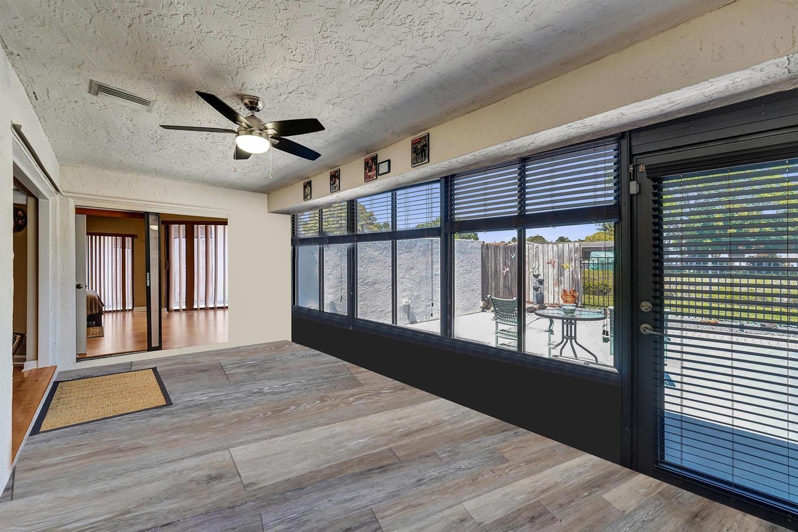 A sunroom with wood-look tile flooring, a ceiling fan, and large windows overlooking a patio — 9355 NW 18th Drive, Plantation FL 33322, PLANTATION, FL