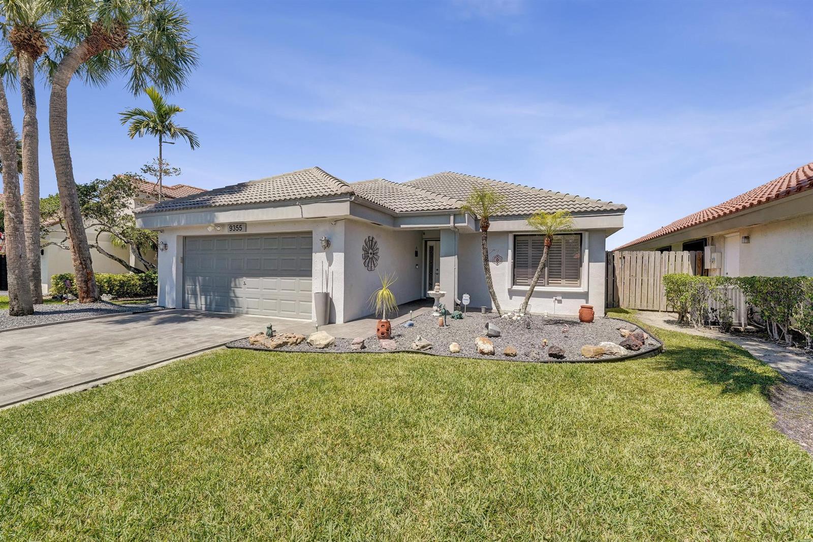 A single-story house with a gray garage, tiled roof, and a landscaped rock garden — 9355 NW 18th Drive, Plantation FL 33322, PLANTATION, FL