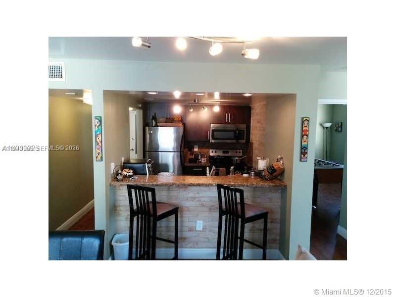 A kitchen features dark cabinets, stainless steel appliances, and a breakfast bar with two stools — 800 N Miami Ave # 1108, Miami FL 33136, MIAMI, FL
