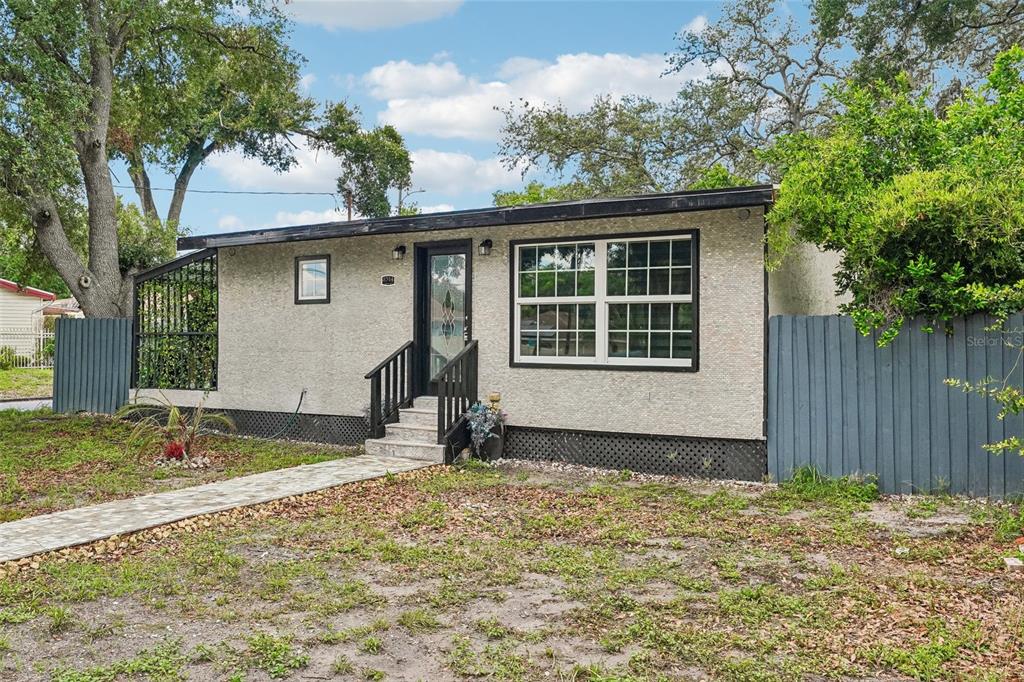 A single-story house with a textured beige exterior, black trim, and a front walkway — 8514 N BRANCH AVENUE, TAMPA, FL