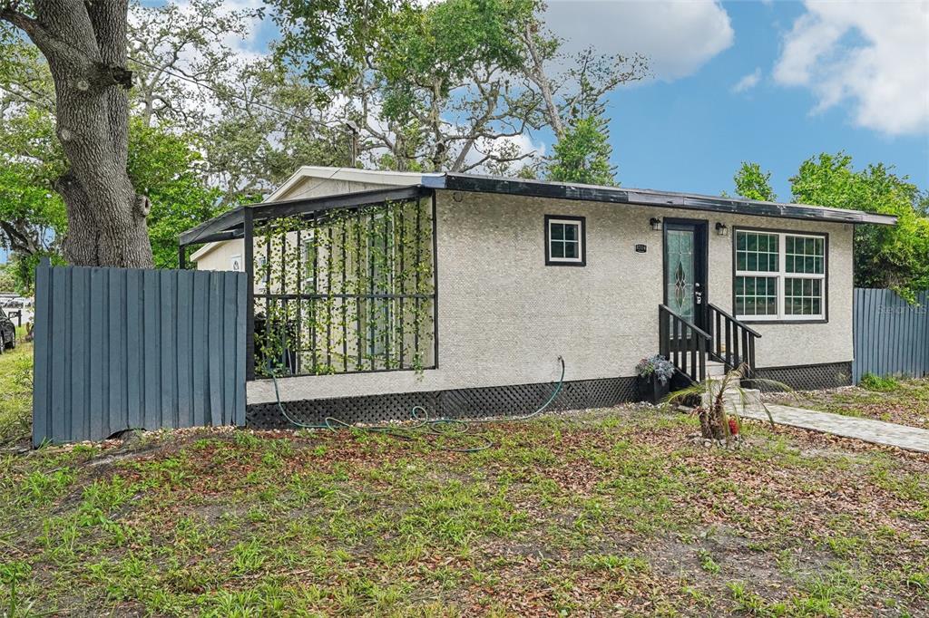A single-story house with a stucco exterior, a front porch, and a fenced-in side patio — 8514 N BRANCH AVENUE, TAMPA, FL