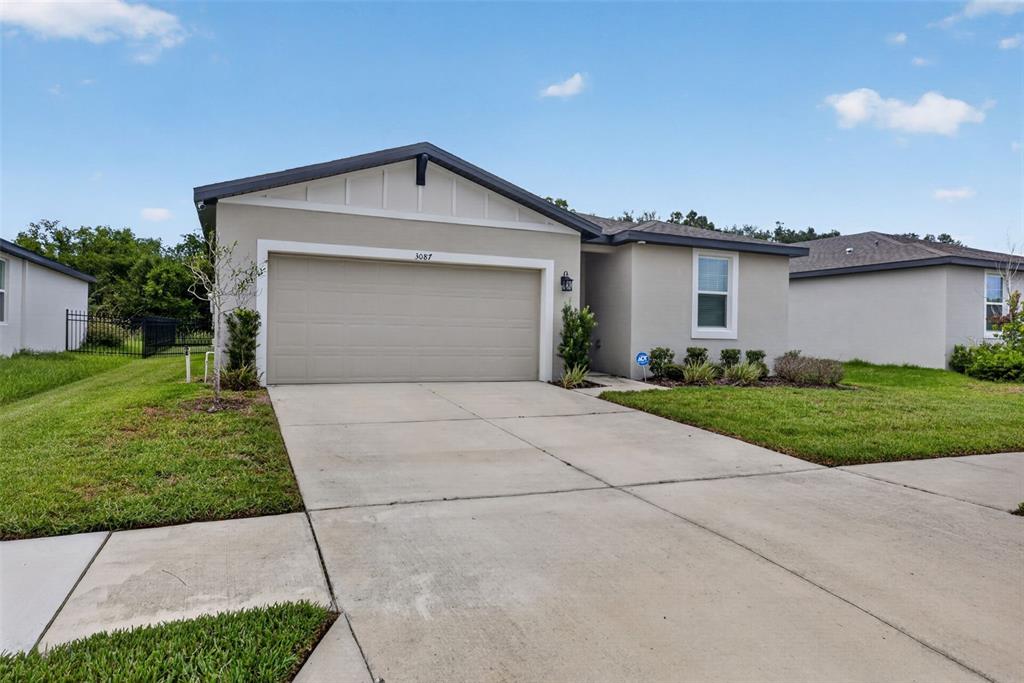 A single-story house with a beige stucco exterior, a two-car garage, and a concrete driveway — 3087 FORREST PLUM COURT, ZEPHYRHILLS, FL