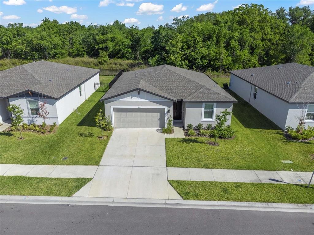 An exterior view of a single-story suburban house with a gray roof and garage — 3087 FORREST PLUM COURT, ZEPHYRHILLS, FL