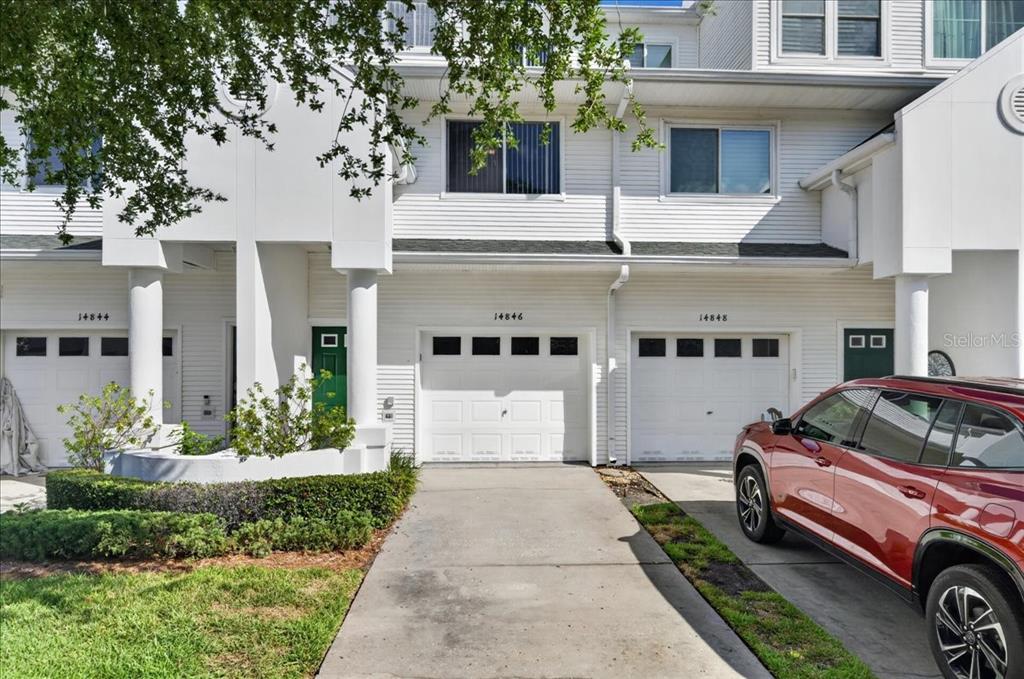 A green front door sits next to a white garage door on a residential building — 14846 SEMINOLE TRAIL, SEMINOLE, FL