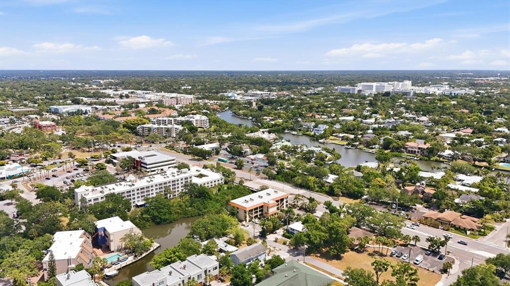 An aerial view shows a suburban area with buildings, a winding canal, and roads — 1650 PINE TREE LANE UNIT 103, SARASOTA, FL