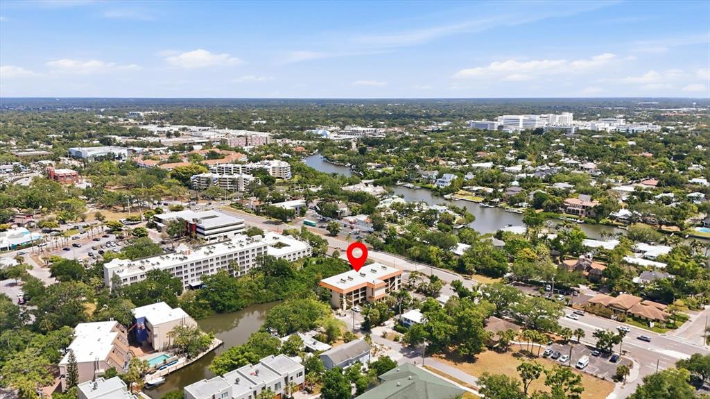 An aerial view shows a multi-story building marked with a red pin near a waterway — 1650 PINE TREE LANE UNIT 103, SARASOTA, FL