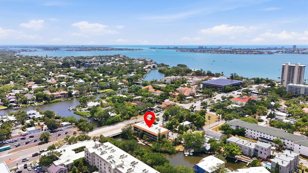 An aerial view shows a multi-story apartment building marked with a red pin near water — 1650 PINE TREE LANE UNIT 103, SARASOTA, FL