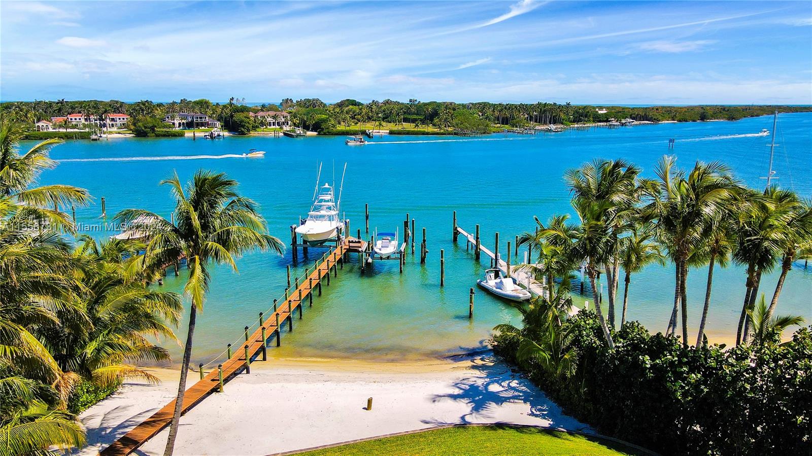 A private wooden dock with three boats extends into a bright blue tropical waterway — 17581 SE Conch Bar Ave, Jupiter FL 33469, JUPITER, FL
