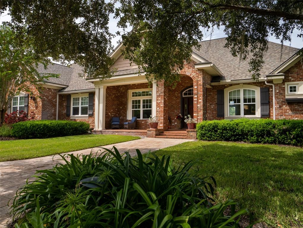 A brick house with a covered front porch, arched entryway, and manicured landscaping — 15122 NW 41ST AVENUE, NEWBERRY, FL