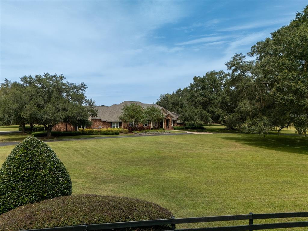 A brick house sits behind a large green lawn surrounded by mature oak trees — 15122 NW 41ST AVENUE, NEWBERRY, FL