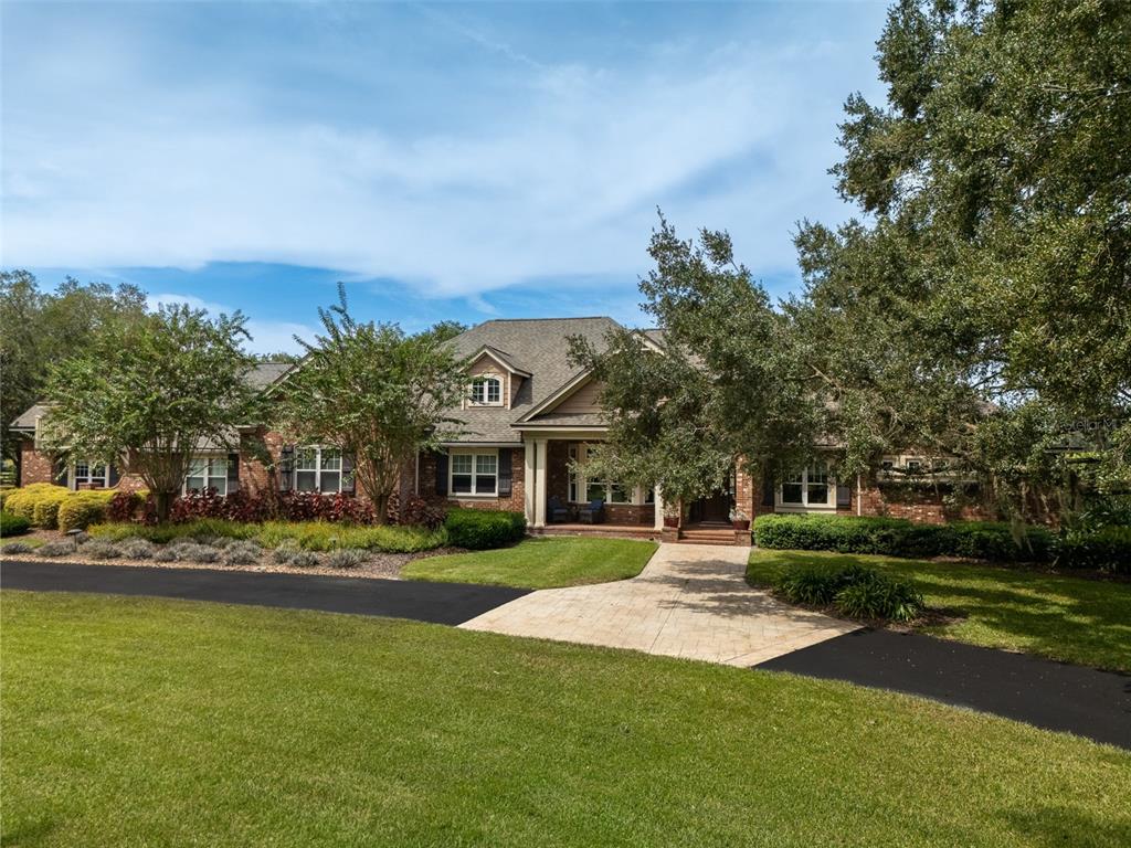 A brick house with a shingled roof, a paved walkway, and mature trees in front — 15122 NW 41ST AVENUE, NEWBERRY, FL