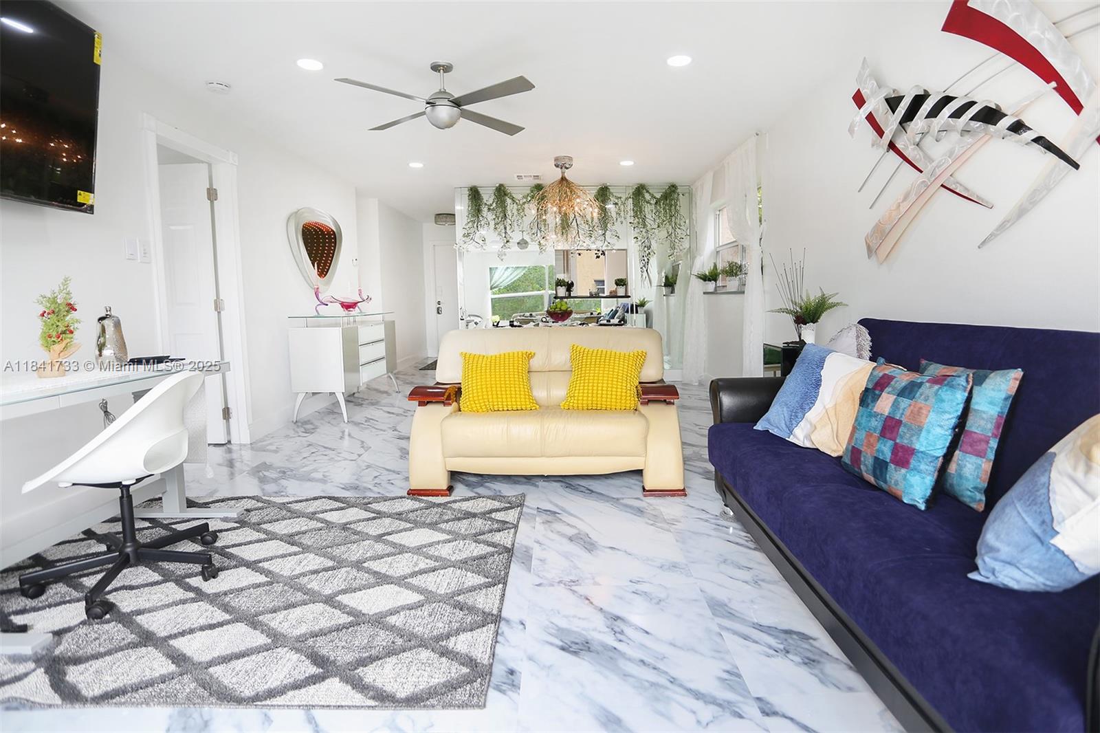 A living room features marble floors, a beige sofa, a blue couch, and a desk — 6570 Royal Palm Blvd # 301J, Margate FL 33063, MARGATE, FL