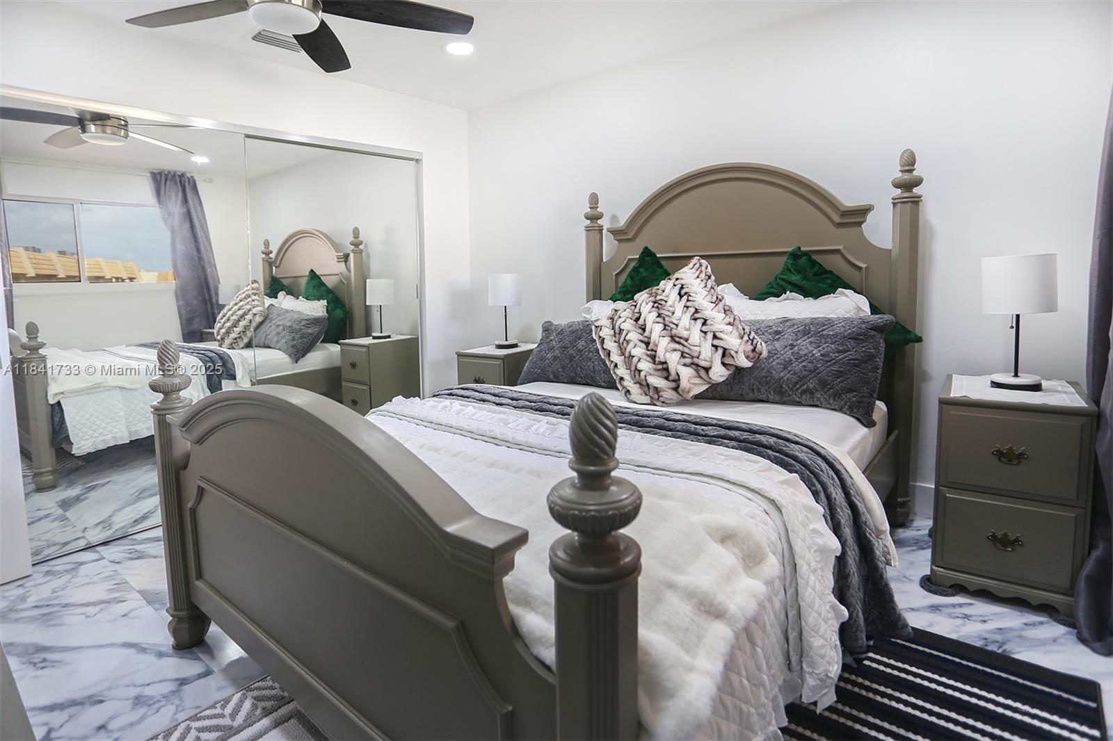 A bedroom features a gray wooden bed frame, mirrored closet doors, and marble-patterned flooring — 6570 Royal Palm Blvd # 301J, Margate FL 33063, MARGATE, FL