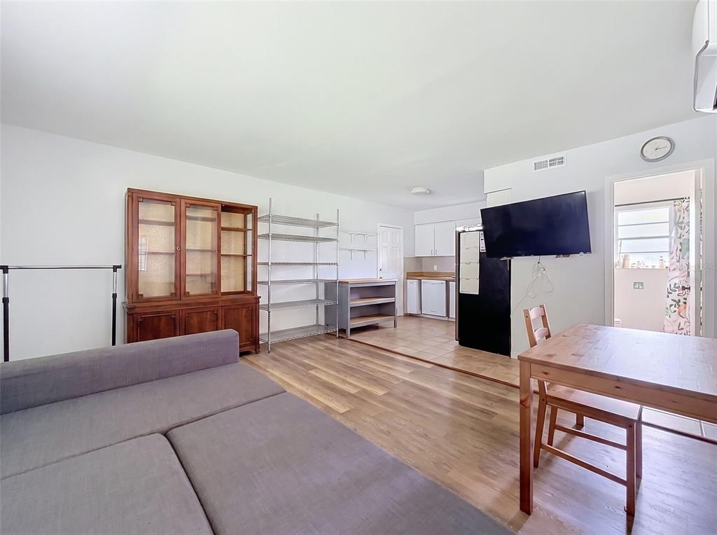 A living room with wood-look flooring flows into a kitchen with tile flooring — 7995 53RD WAY N, PINELLAS PARK, FL