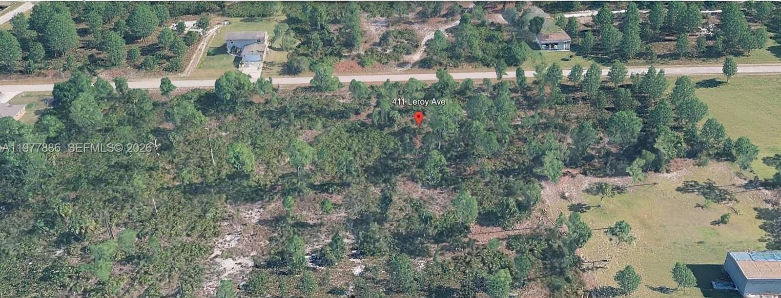 An aerial view shows a heavily wooded, undeveloped residential lot with scattered pine trees — 411 LEROY AVE, Lehigh Acres FL 33972, LEHIGH ACRES, FL