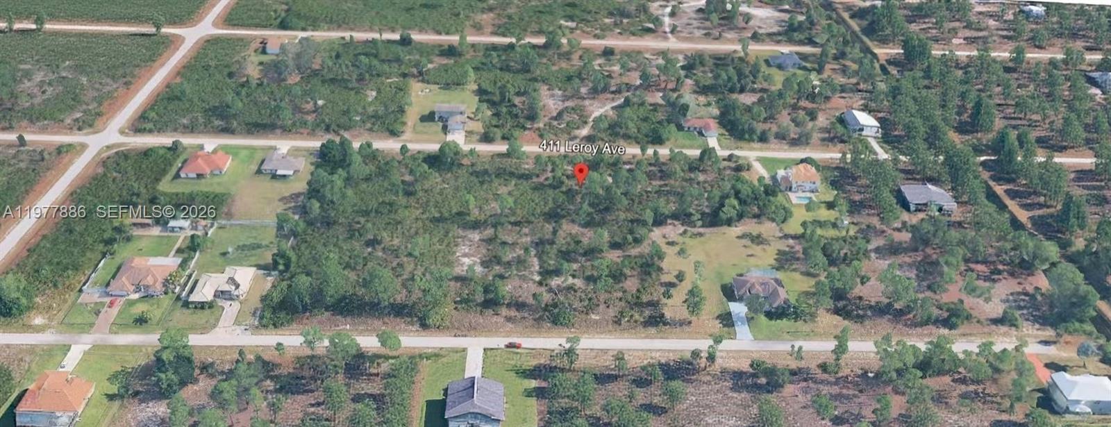 An aerial view shows a vacant, wooded residential lot surrounded by houses and paved roads — 411 LEROY AVE, Lehigh Acres FL 33972, LEHIGH ACRES, FL