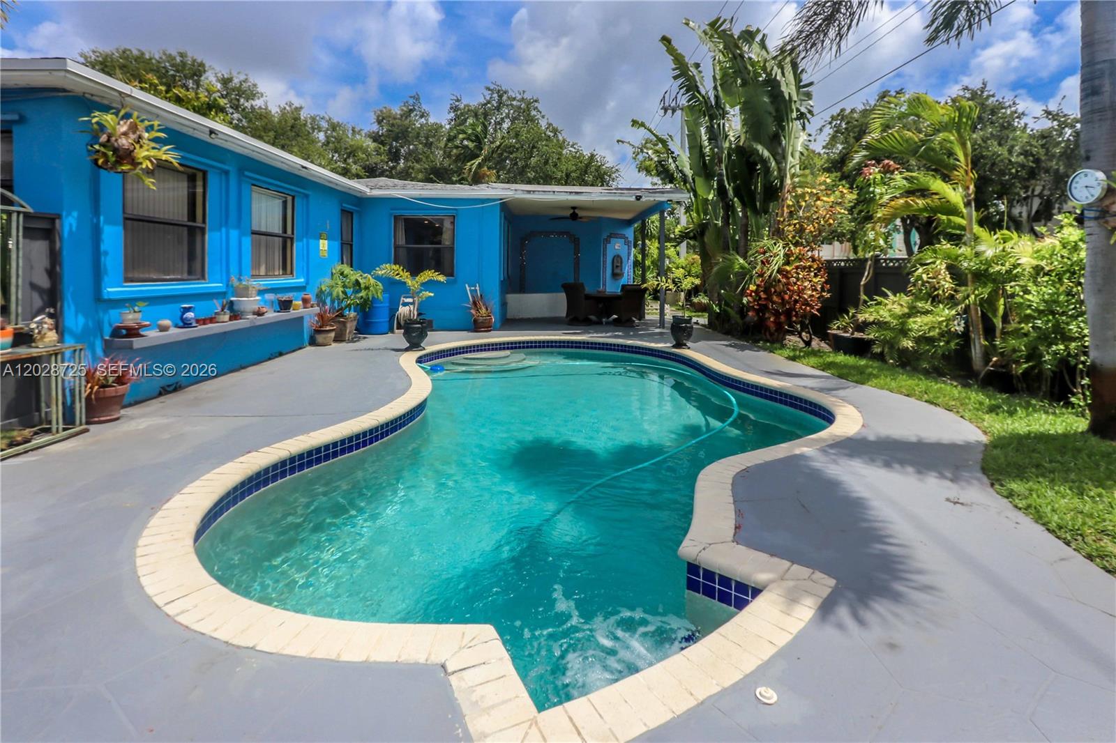 A bright blue house features a kidney-shaped swimming pool on a gray concrete patio — 706 S 19th Ave, Hollywood FL 33020, HOLLYWOOD, FL