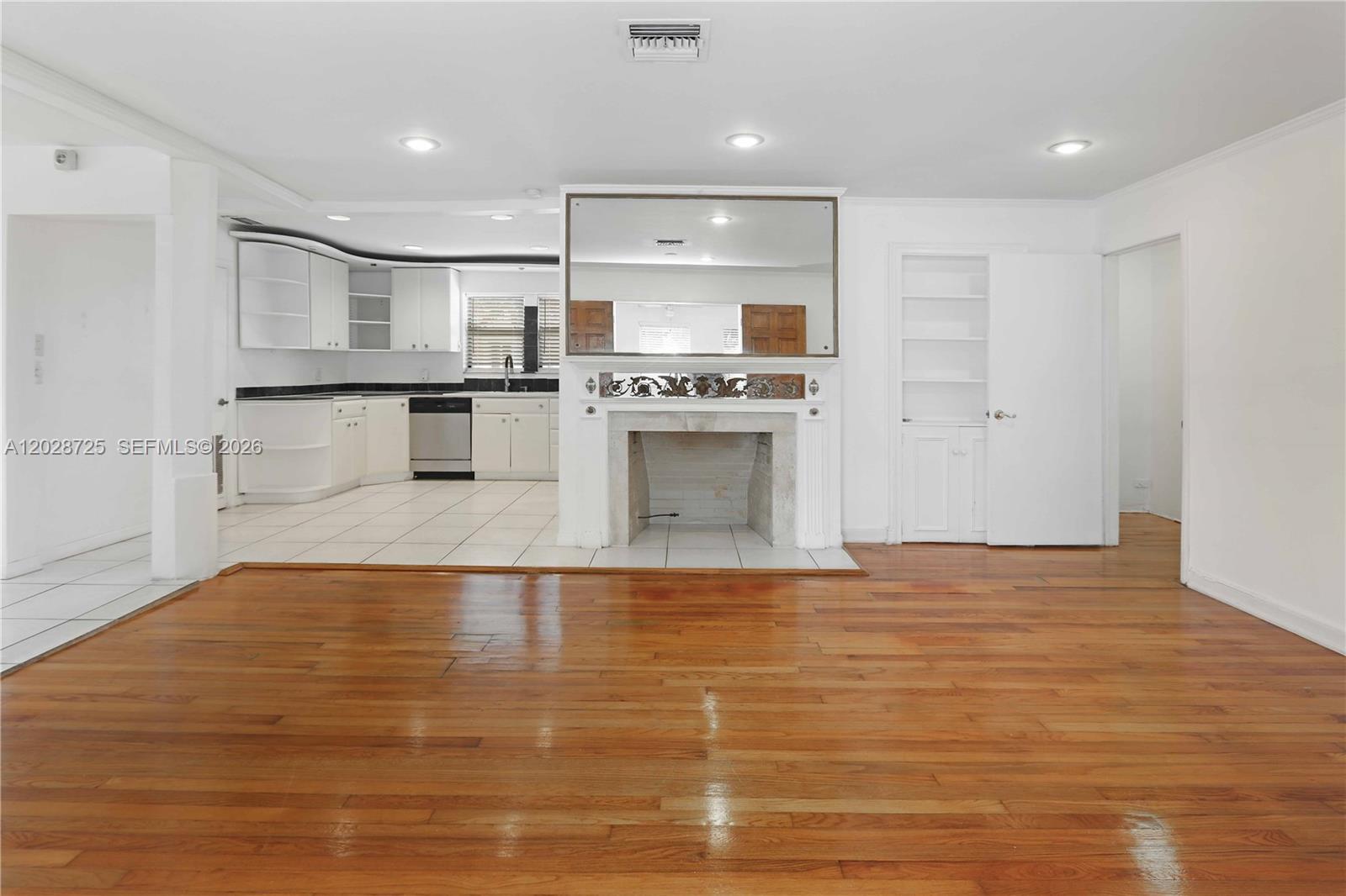 A living room with hardwood floors features a fireplace and an adjacent tiled kitchen — 706 S 19th Ave, Hollywood FL 33020, HOLLYWOOD, FL