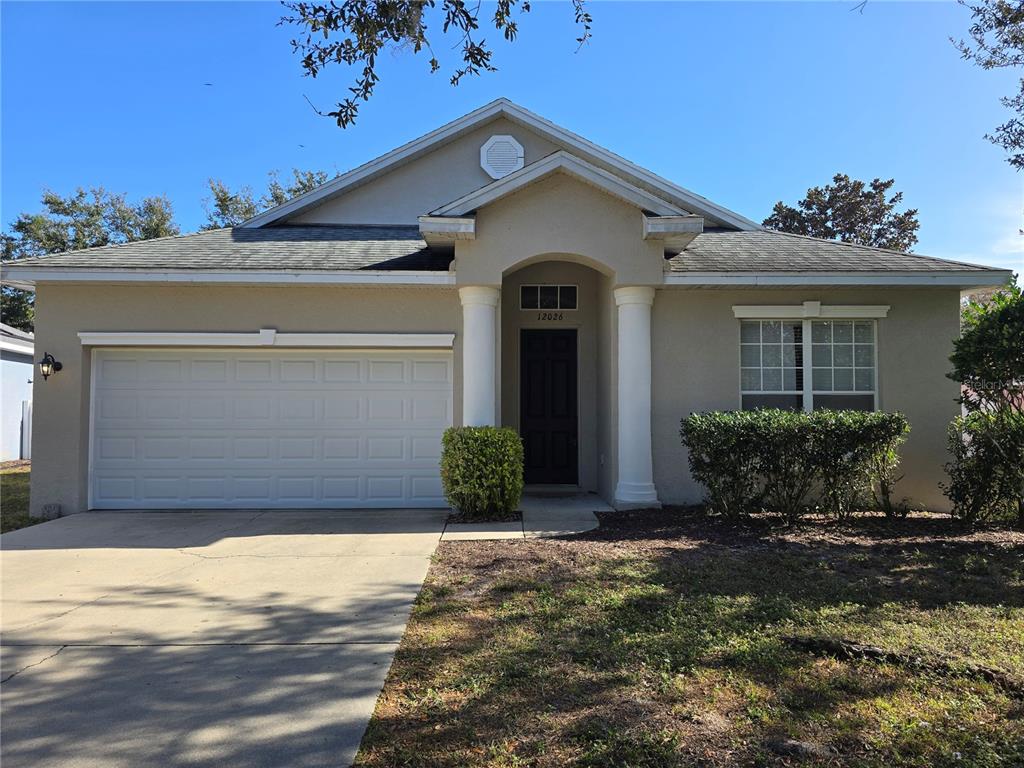 A single-story house with a beige stucco exterior, a two-car garage, and two white columns — 12026 TASHA COURT, NEW PORT RICHEY, FL