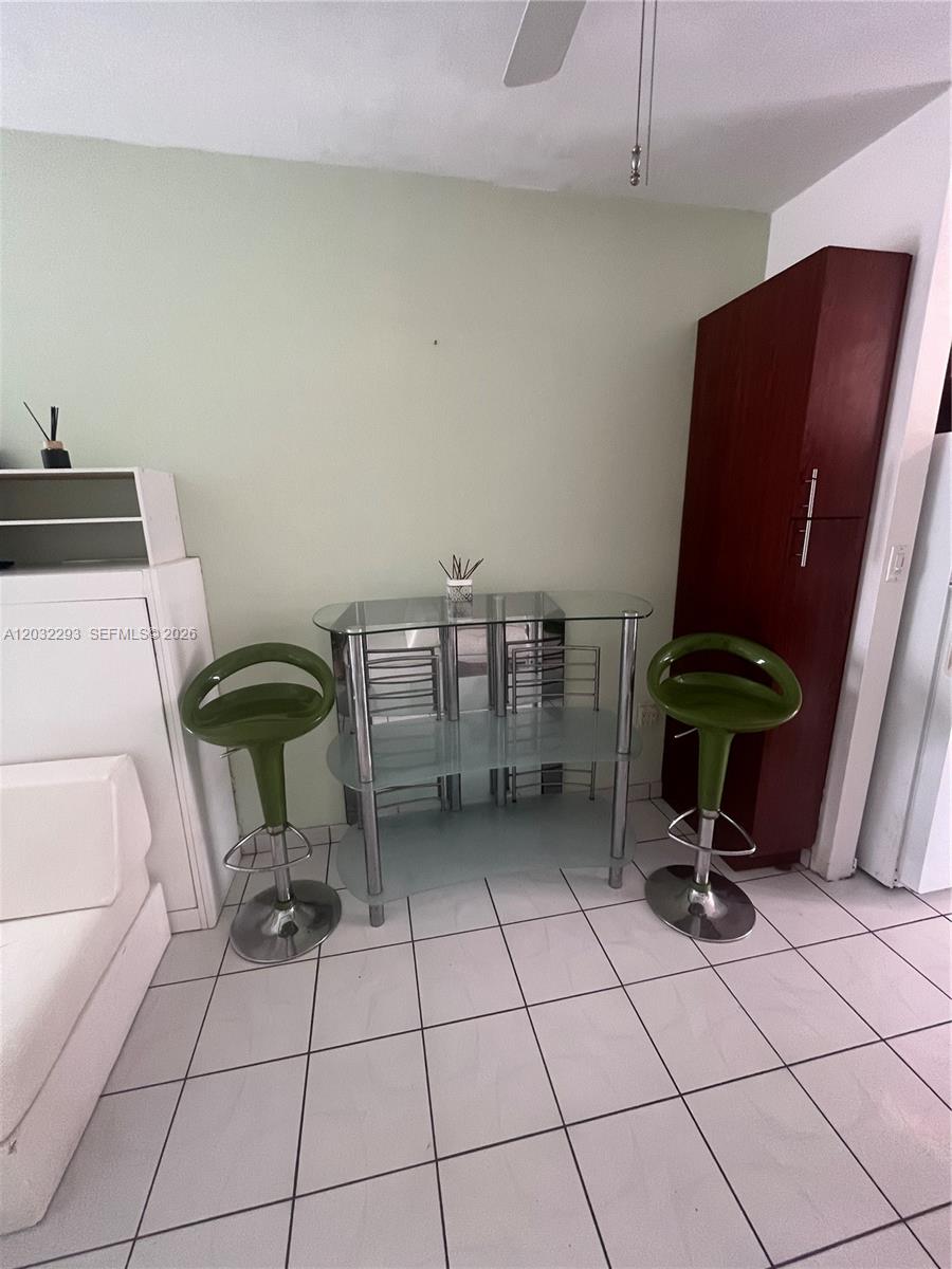 A dining area features a glass table, two green bar stools, and white tile flooring — 851 Meridian Ave # 44, Miami Beach FL 33139, MIAMI BEACH, FL