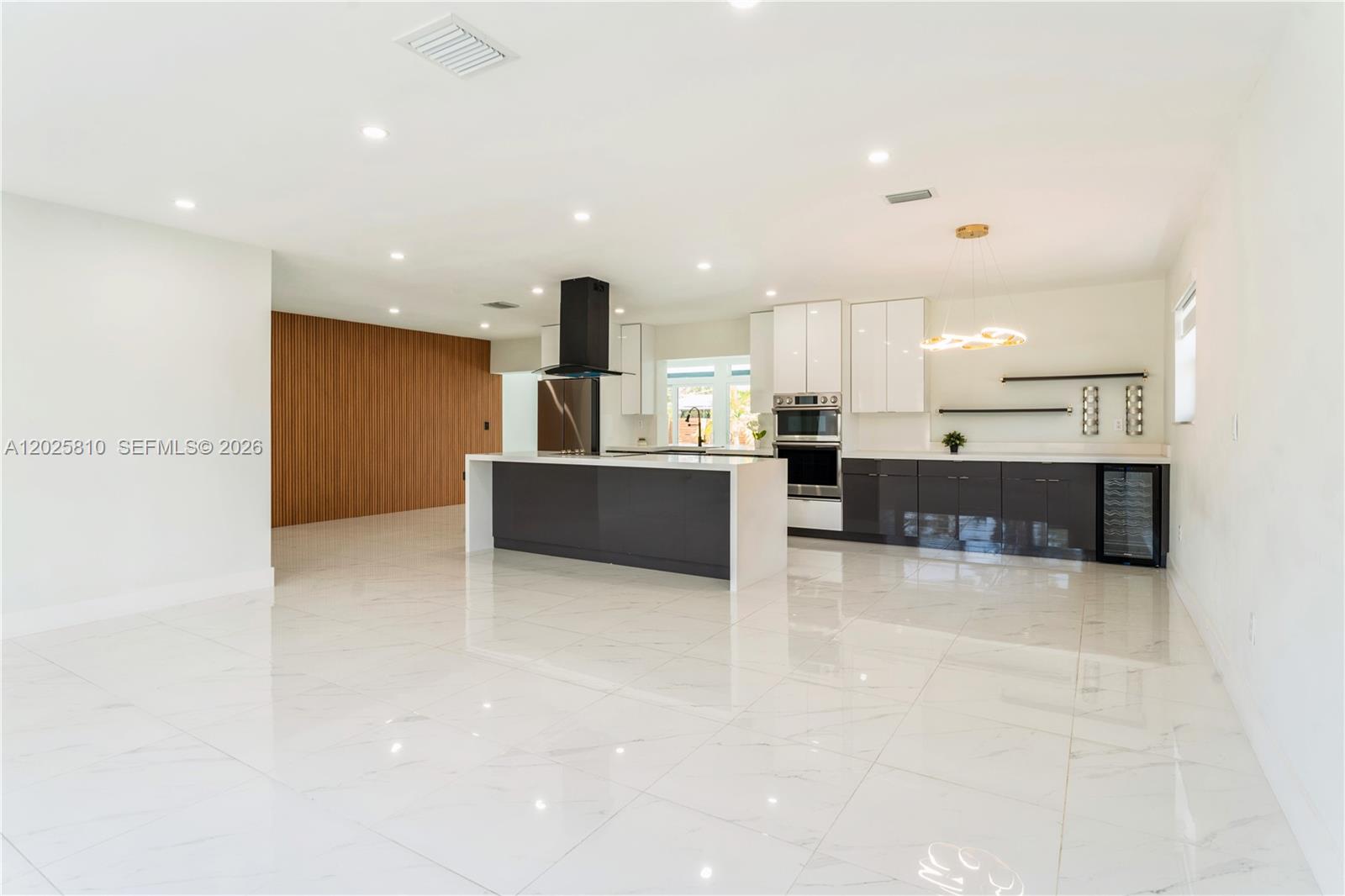 A modern kitchen features a large island, dark lower cabinets, white upper cabinets, and tile flooring — 1446 Scott St, Hollywood FL 33020, HOLLYWOOD, FL