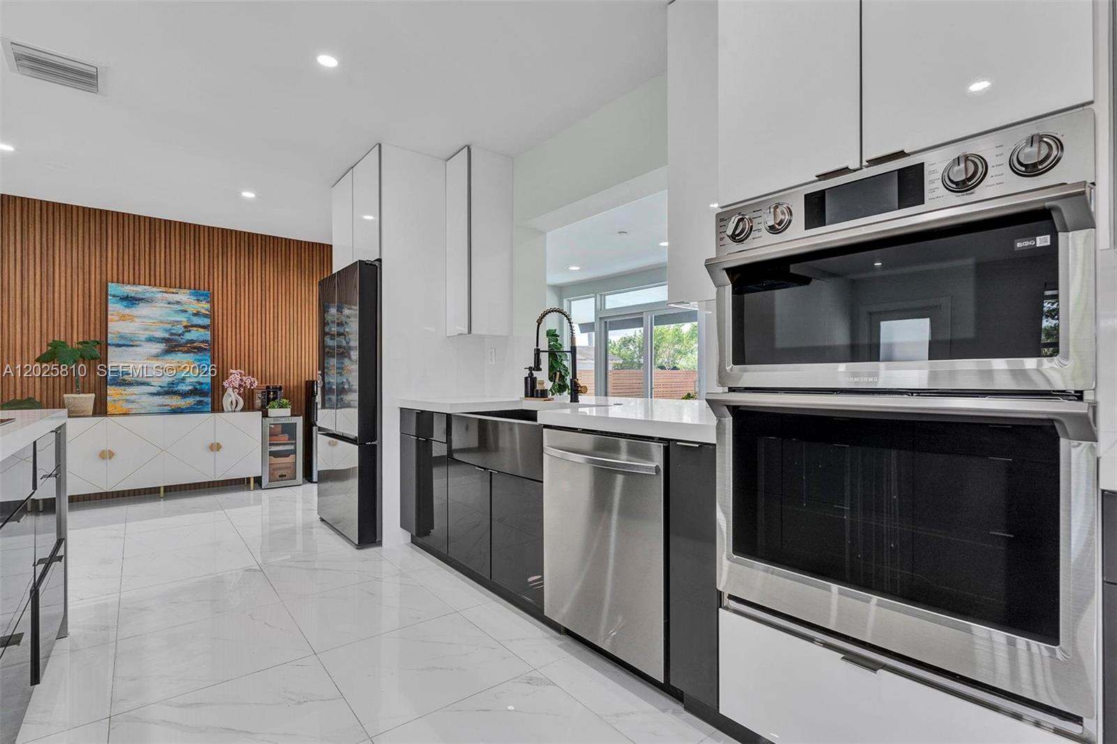 A modern kitchen features dark cabinetry, stainless steel appliances, and a wood-slatted accent wall — 1446 Scott St, Hollywood FL 33020, HOLLYWOOD, FL