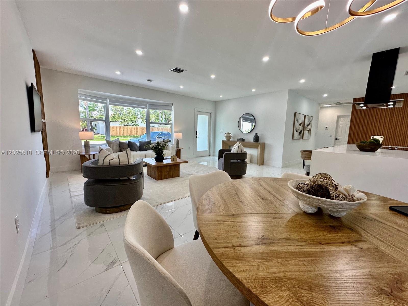 An open-concept living and dining area features white marble floors, modern furniture, and recessed lighting — 1446 Scott St, Hollywood FL 33020, HOLLYWOOD, FL