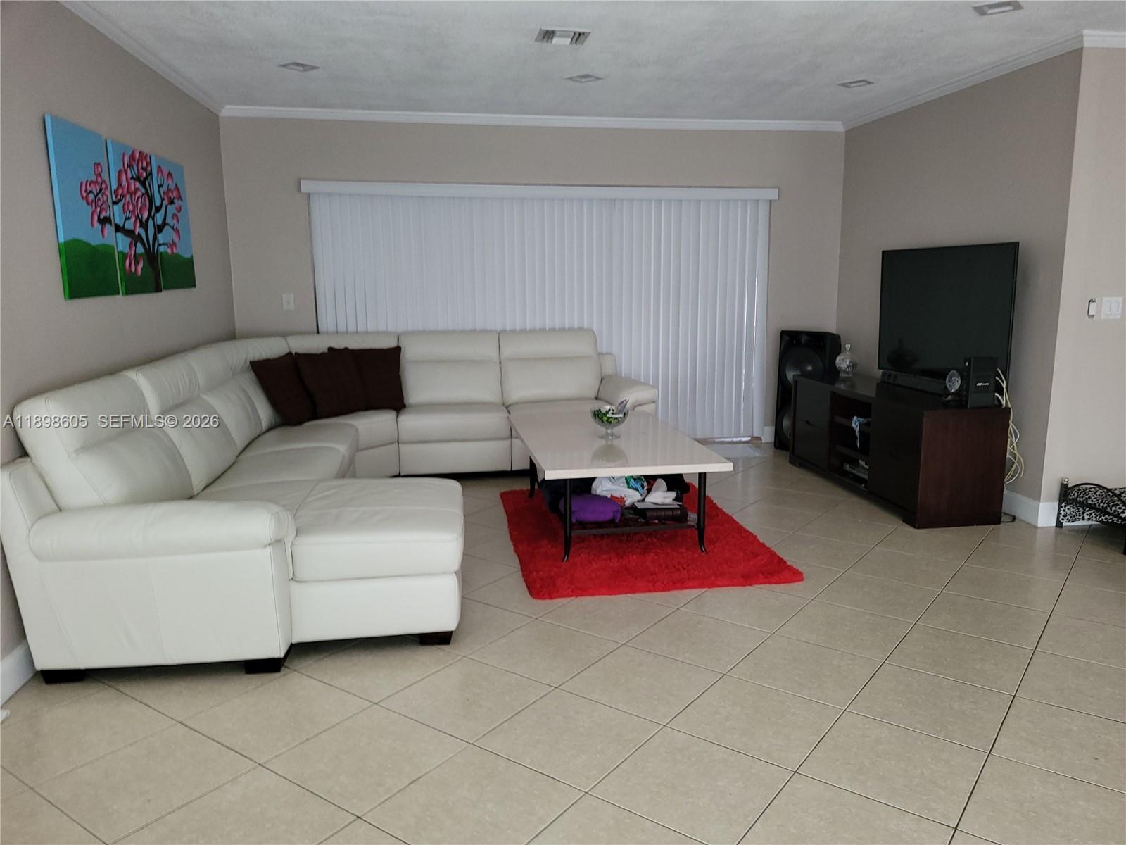 A living room features a white sectional sofa, a red rug, and a television console — SOUTH MIAMI, FL