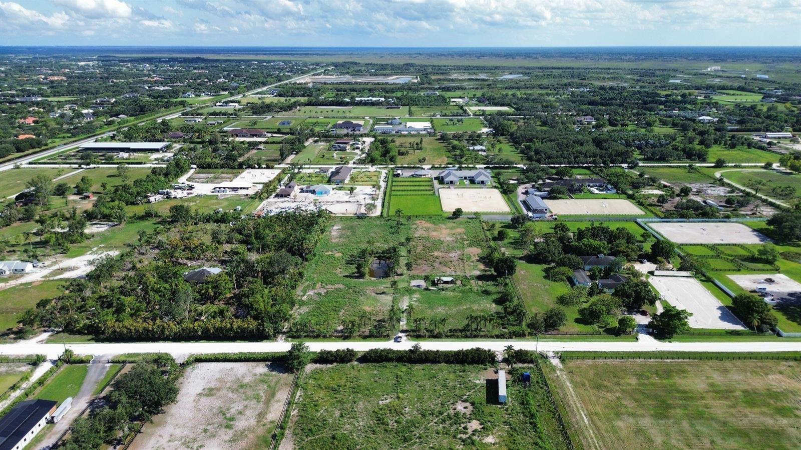 An aerial view shows a rural landscape with scattered houses, horse paddocks, and open fields — 16290 Rustic Road, Wellington FL 33470, WELLINGTON, FL