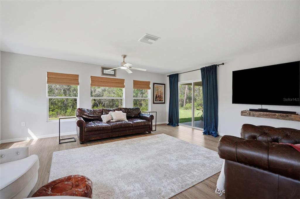 A living room features leather sofas, a large area rug, and sliding glass patio doors — 8477 BEACHWOOD COURT, SPRING HILL, FL