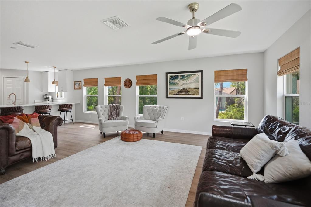 A living room with leather sofas, two armchairs, and an open kitchen in the background — 8477 BEACHWOOD COURT, SPRING HILL, FL
