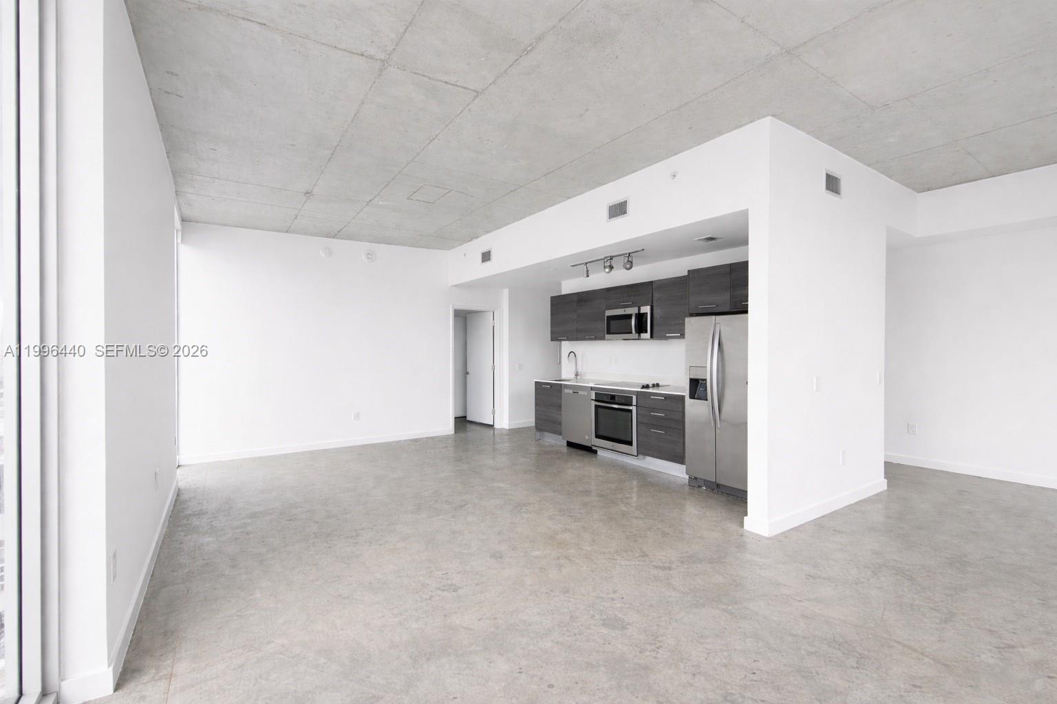 This open-concept living area features a kitchen with dark cabinetry and concrete flooring — 151 SE 1st St # 3001, Miami FL 33131, MIAMI, FL