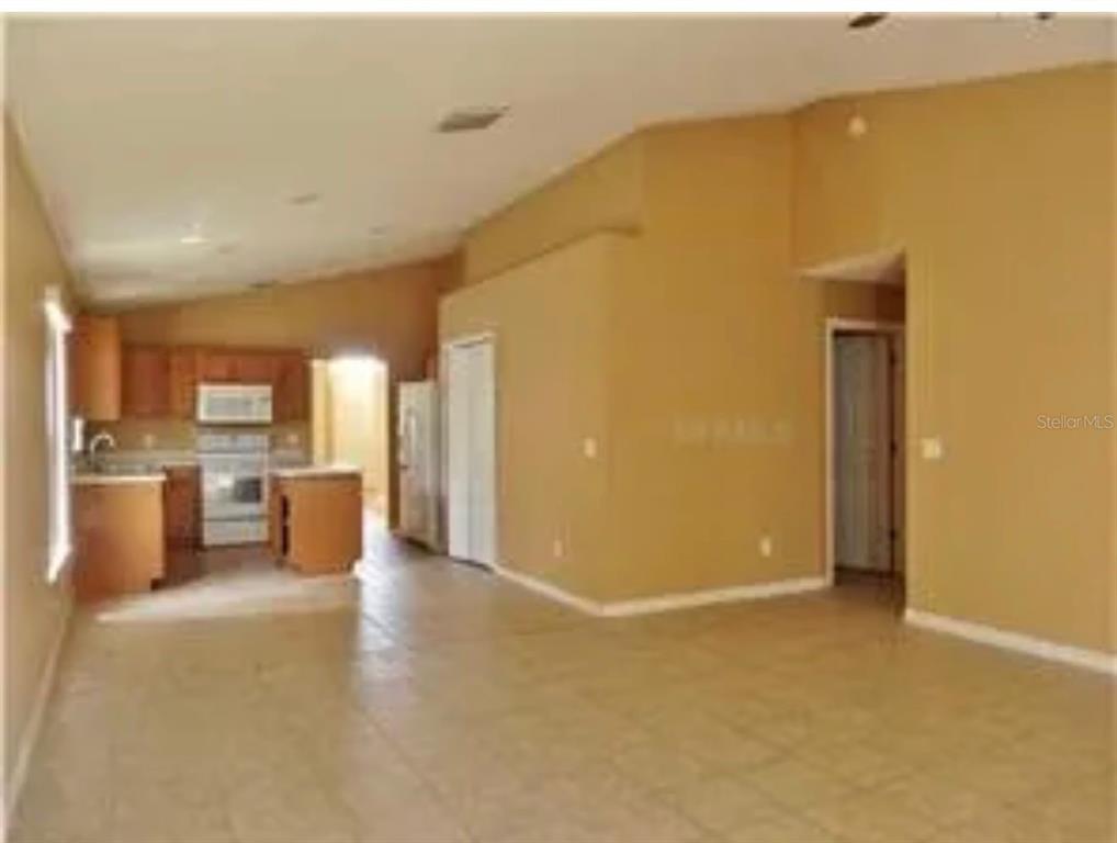 An open-concept living area with tile flooring leads into a kitchen with wood cabinets — 855 BRAYTON LANE, DAVENPORT, FL