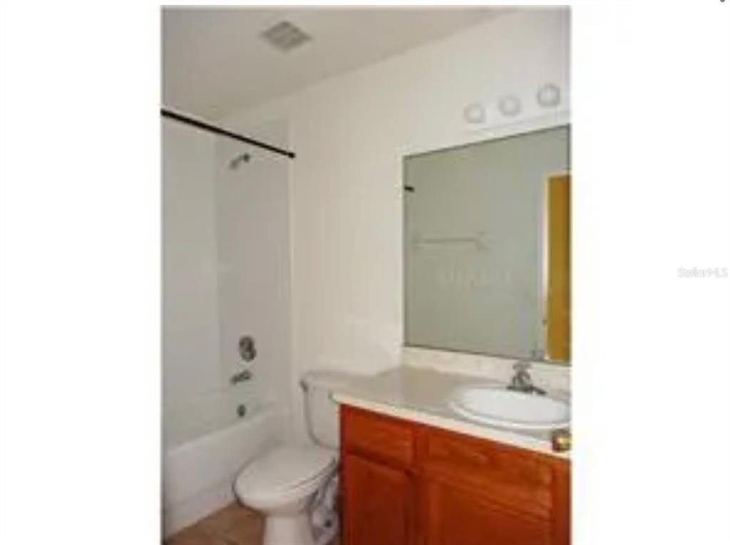 A bathroom features a wooden vanity with a sink, a toilet, and a shower-tub combination — 855 BRAYTON LANE, DAVENPORT, FL