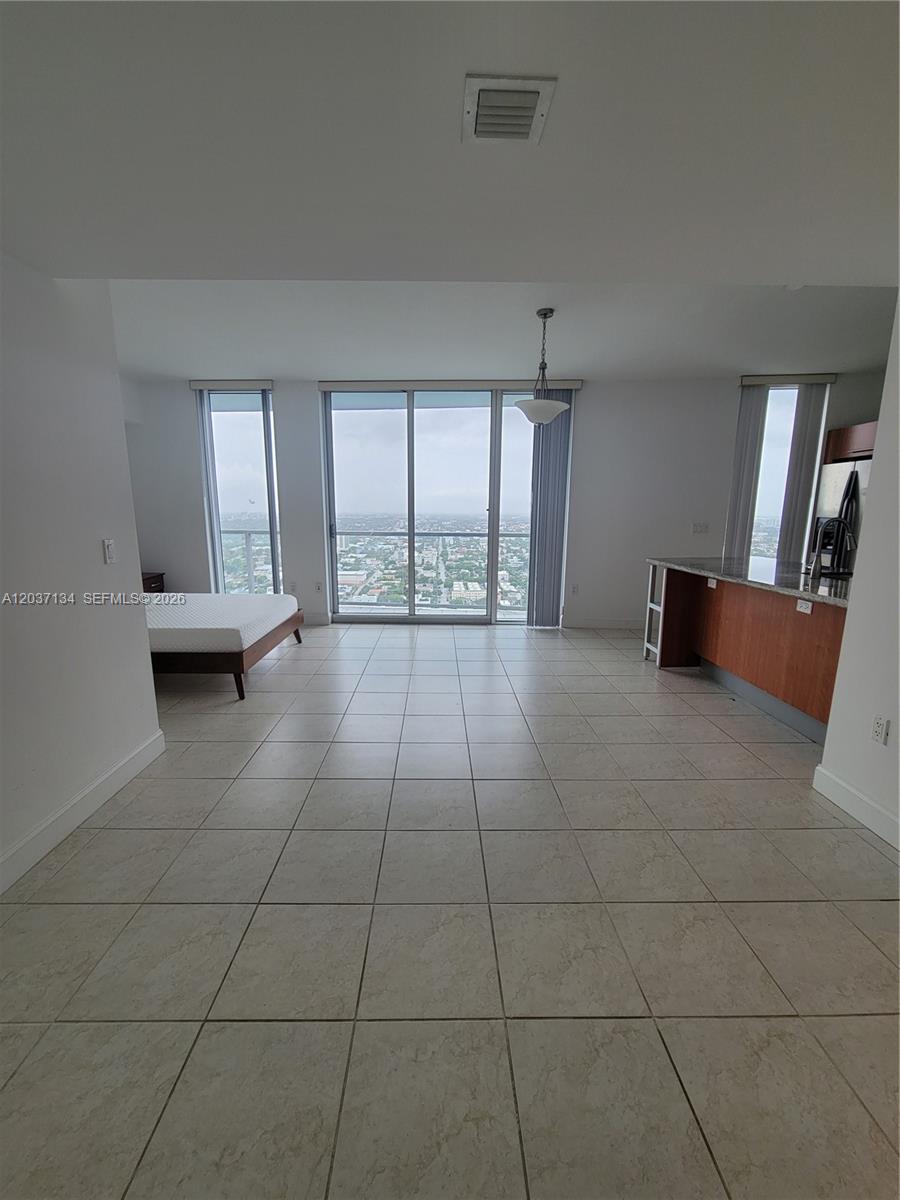 This studio apartment features tile flooring, a kitchen island, and floor-to-ceiling windows with city views — 185 SW 7th St # 3500, Miami FL 33130, MIAMI, FL