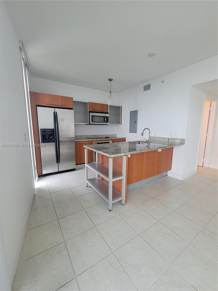 A kitchen features wood cabinets, stainless steel appliances, granite countertops, and a central island — 185 SW 7th St # 3500, Miami FL 33130, MIAMI, FL