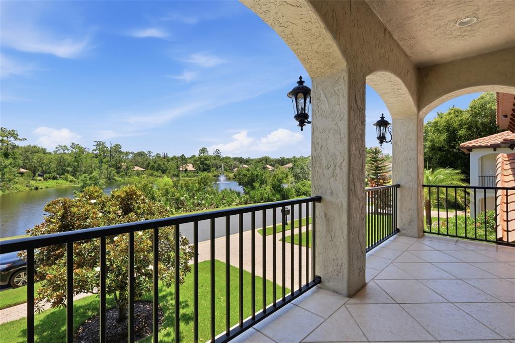 A covered balcony with tile flooring and black railings overlooks a pond and trees — 750 ONYX PARKWAY, DELAND, FL