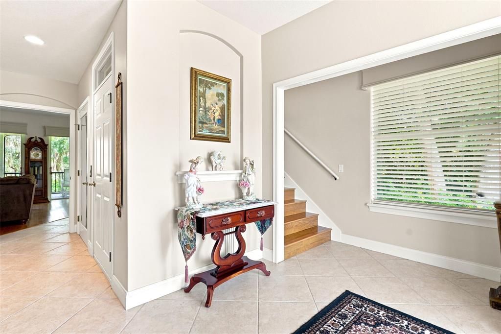 A foyer features tile flooring, a wooden console table, a staircase, and a framed wall art — 750 ONYX PARKWAY, DELAND, FL