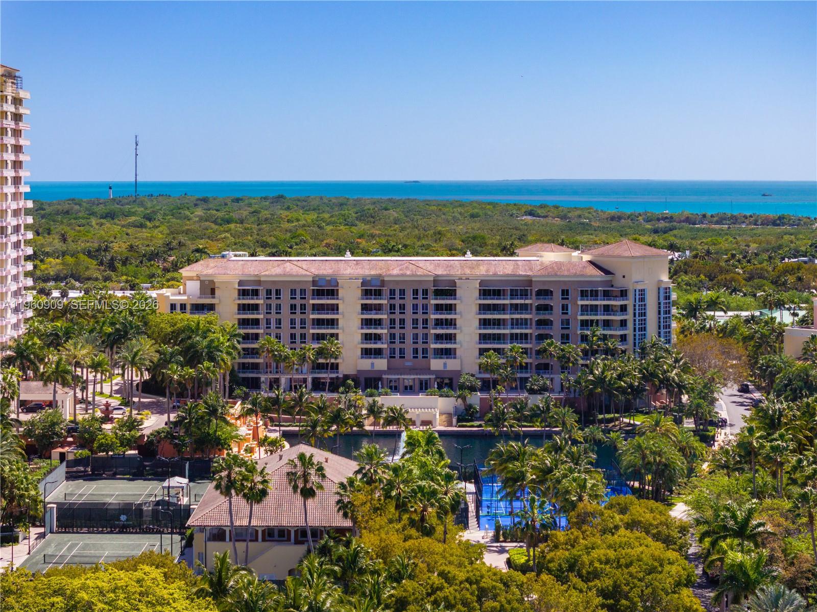 An aerial view shows a large multi-story residential building surrounded by palm trees and tennis courts — 765 Crandon Blvd # 306, Key Biscayne FL 33149, KEY BISCAYNE, FL